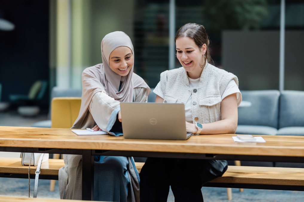 Sumaya werkt achter de laptop samen met een andere collega