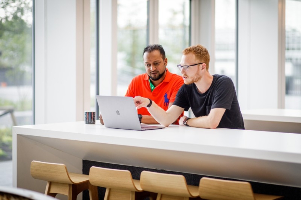 Simon en zijn collega overleggen samen achter de computer