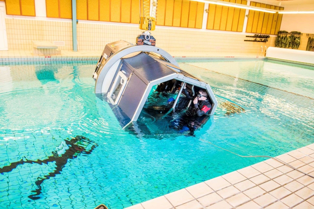 Installatie voor een watersurvivaltraining, de Helo Dunker, in een zwembad.