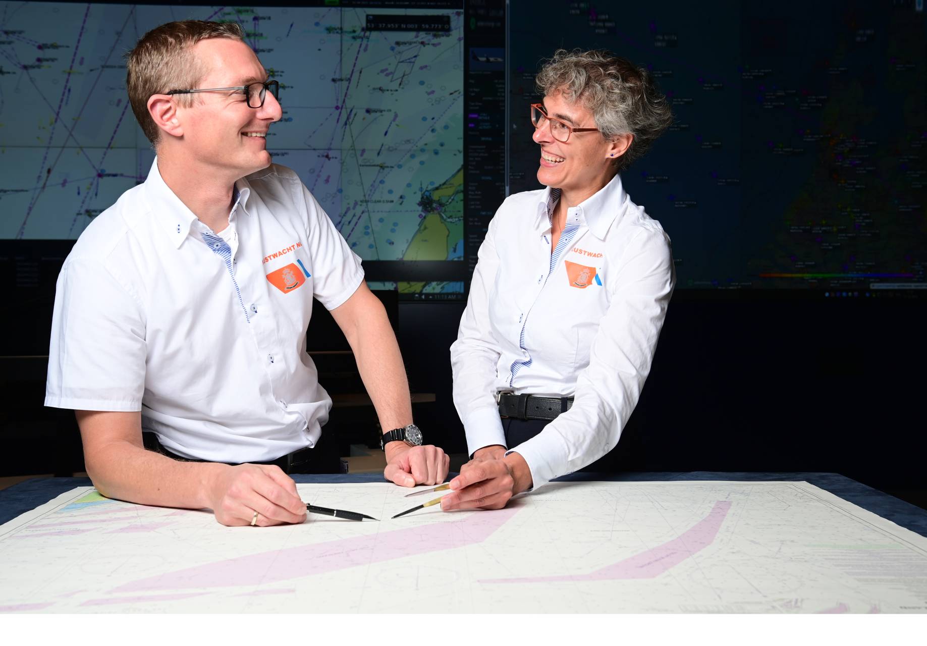 2 collega's van de Kustwacht kijken elkaar lachend aan
