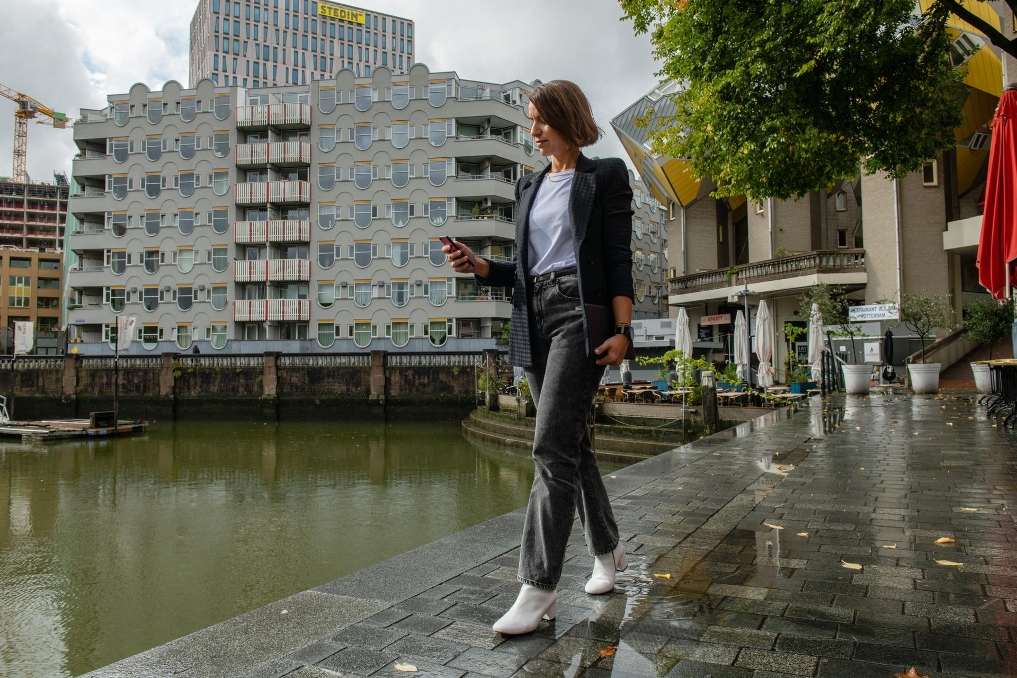 Huriye Akdemir loopt, terwijl zij op haar telefoon kijkt langs het water in Rotterdam