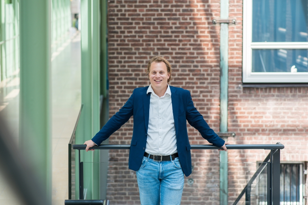 Ivar gefotografeerd op de trap. Hij is beleidsmedewerker bij EZK en werkt aan verduurzaming van de industrie