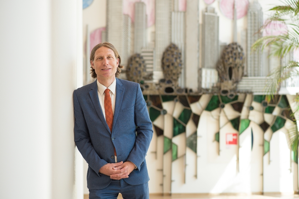 Jarno Dakhorst in de hal op kantoor. Hij is beleidsmedewerker bij EZK en werkt aan de verduurzaming van de industrie in Nederland