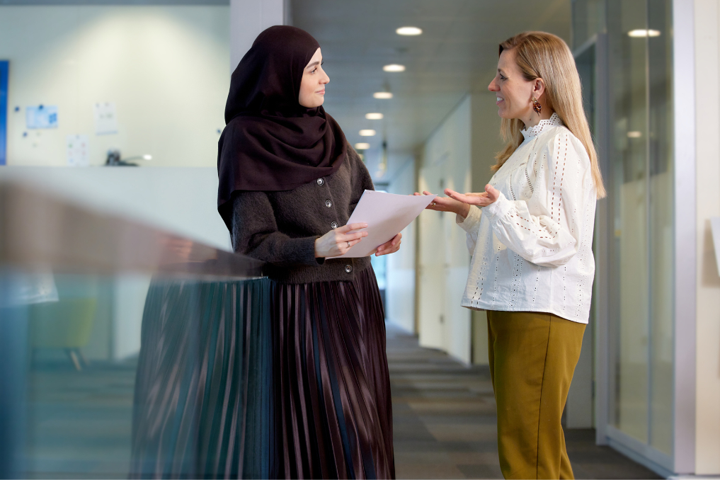Liesbeth in gesprek met collega Farhena. Ze werken aan een nieuw belastingstelsel bij het ministerie van Financiën
