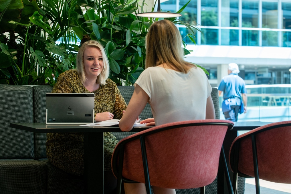 Michelle Kroon en een collega zitten samen aan een tafel en overleggen met elkaar