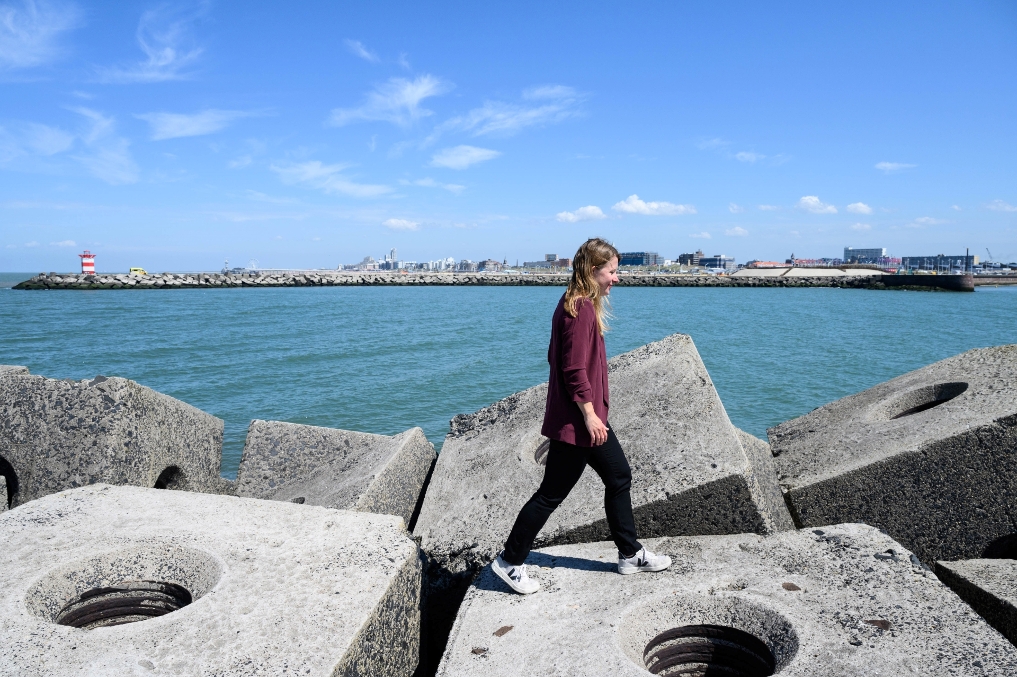 Rijksmedenwerkster van I&W bij een havenhoofd bij zee