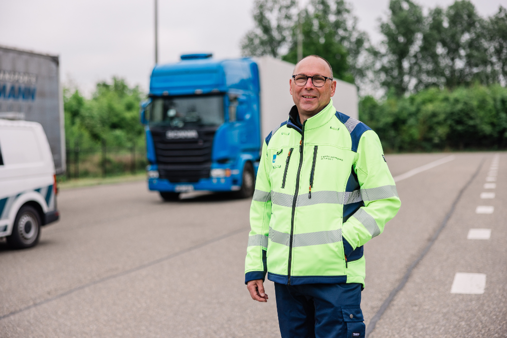 Ron voor een vrachtwagen. Hij is inspecteur vrachtwagenheffing bij de ILT
