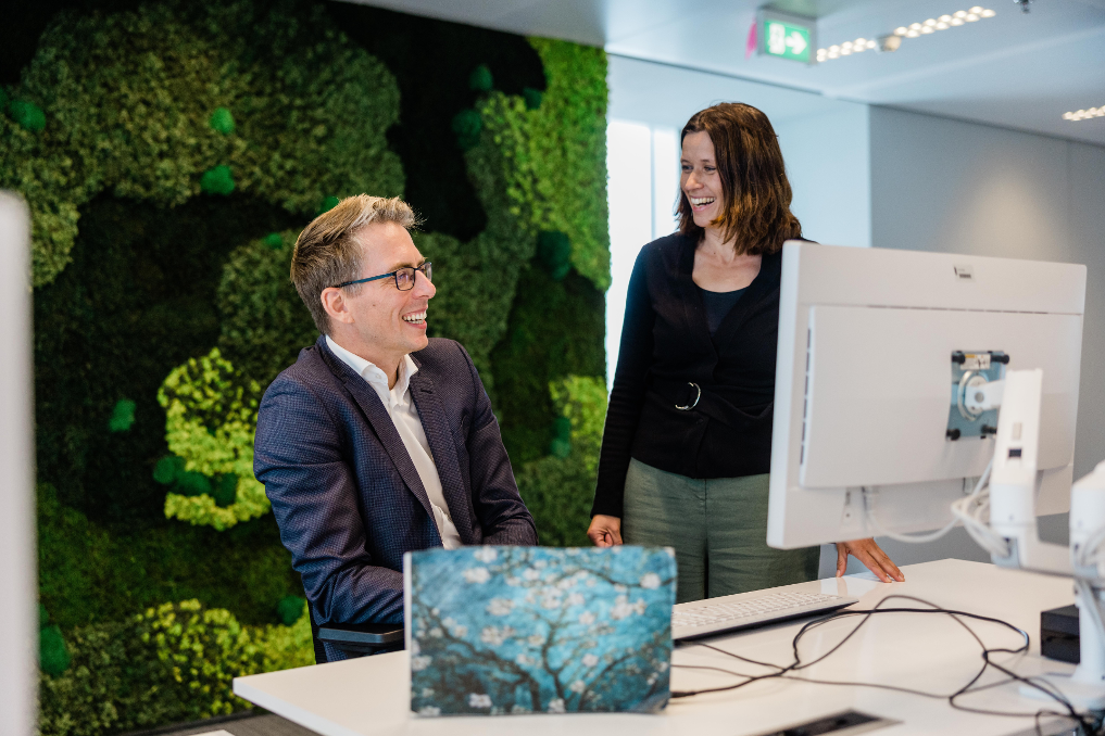 2 collega's bij het ministerie van IenW aan het bureau in gesprek