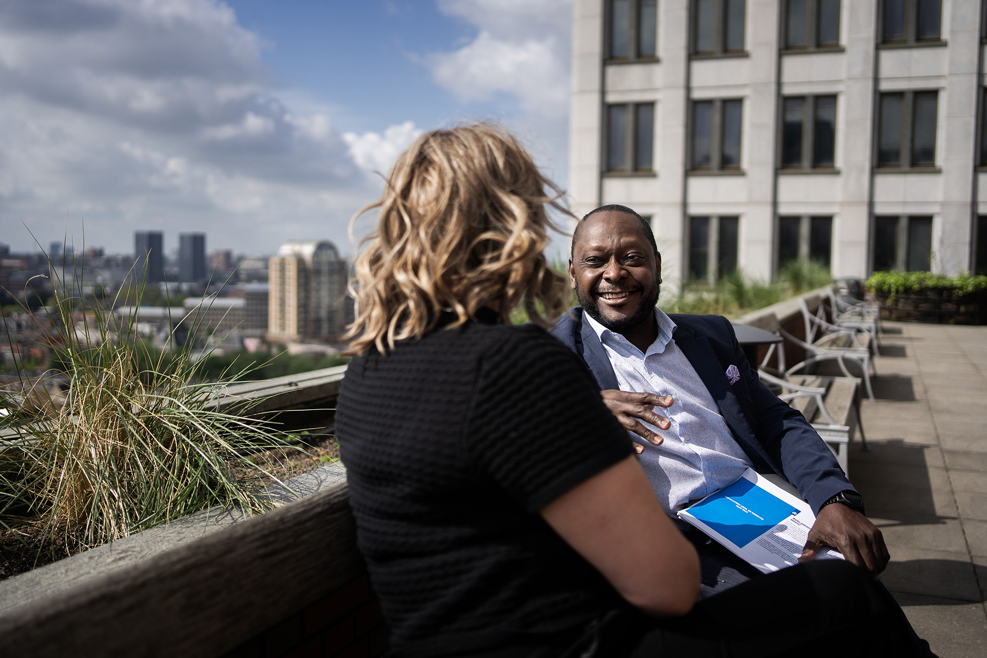 2 collega's samen op een bankje buiten in de zon met elkaar in gesprek