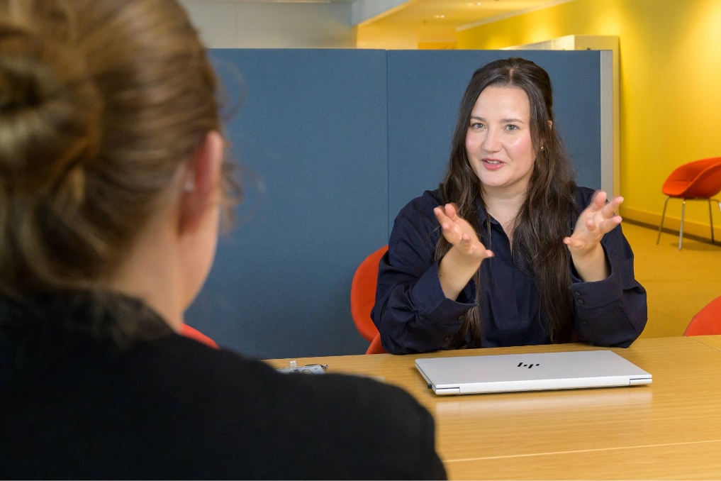 Eva in gesprek met een collega. Ze is beleidsmedewerker bestrijding huiselijk geweld bij het ministerie van JenV