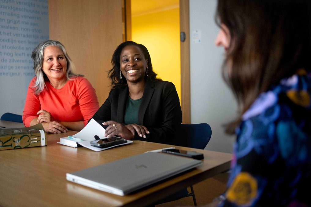 Collega's van JenV met elkaar aan tafel met elkaar in gesprek wetboek ligt op de tafel