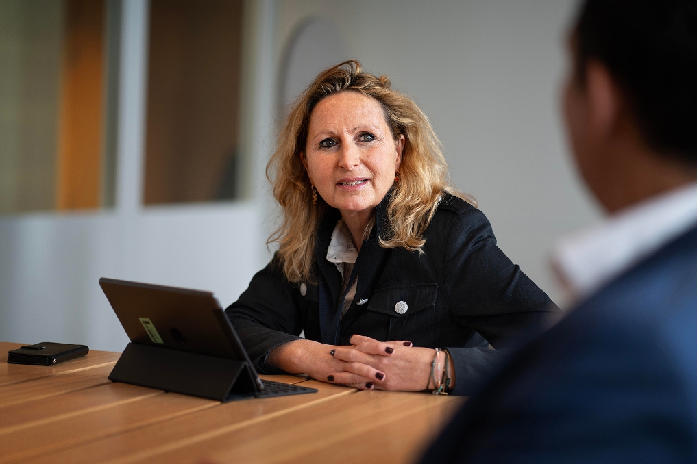 Een collega van JenV achter haar tablet aandachtig aan het luisteren naar een collega