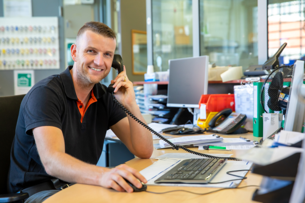 Tommy zit bellend achter zijn bureau