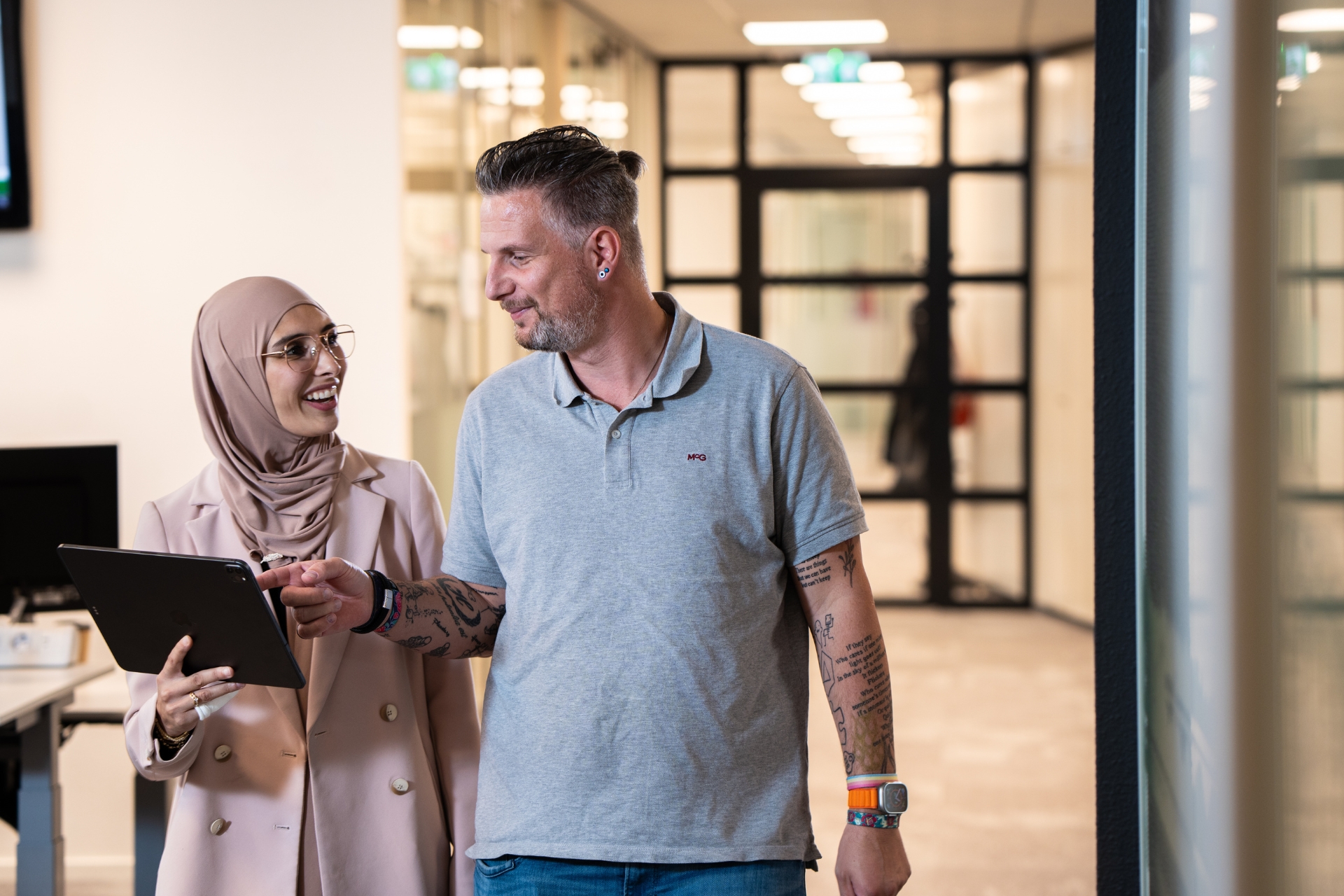 2 collega's lopen samen met elkaar door de gang
