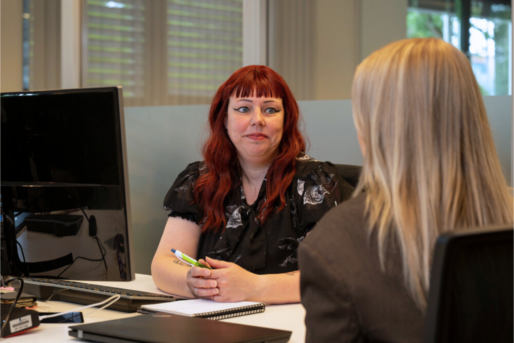Sylvia met een collega in gesprek achter de laptop. Ze is managementassistent bij de NVWA