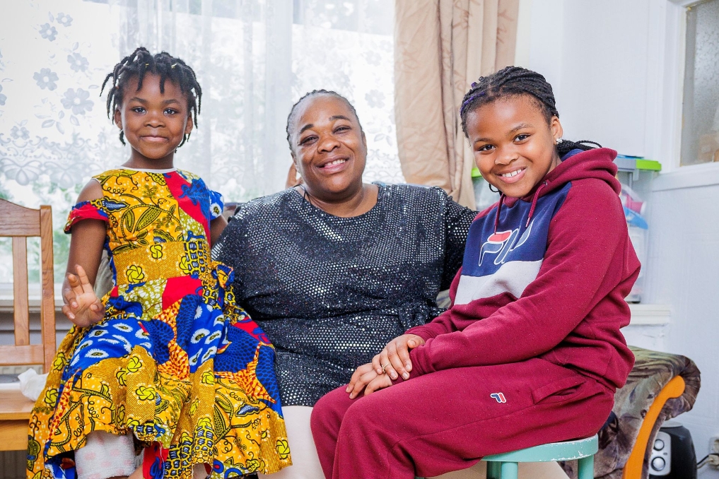 Portret van Femusu met 2 van haar kinderen. Zij werkt als schoonmaakmedewerker bij de Rijksschoonmaakorganisatie