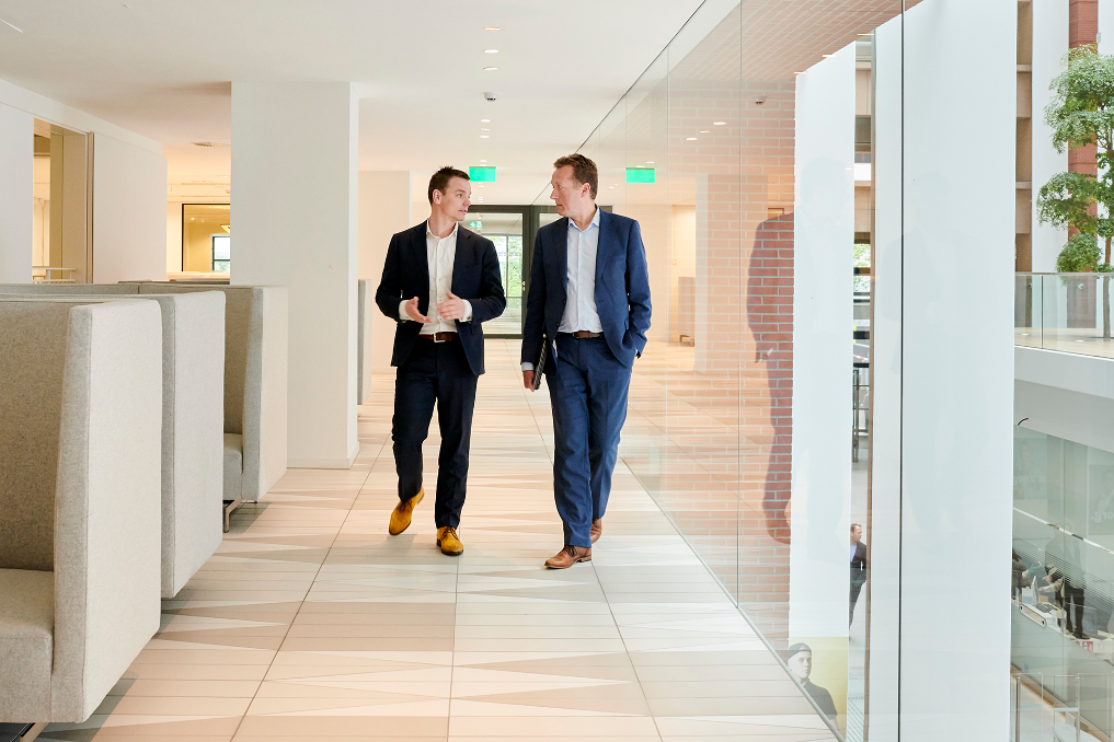 Foto van Groot en Baars lopend door kantoorgebouw