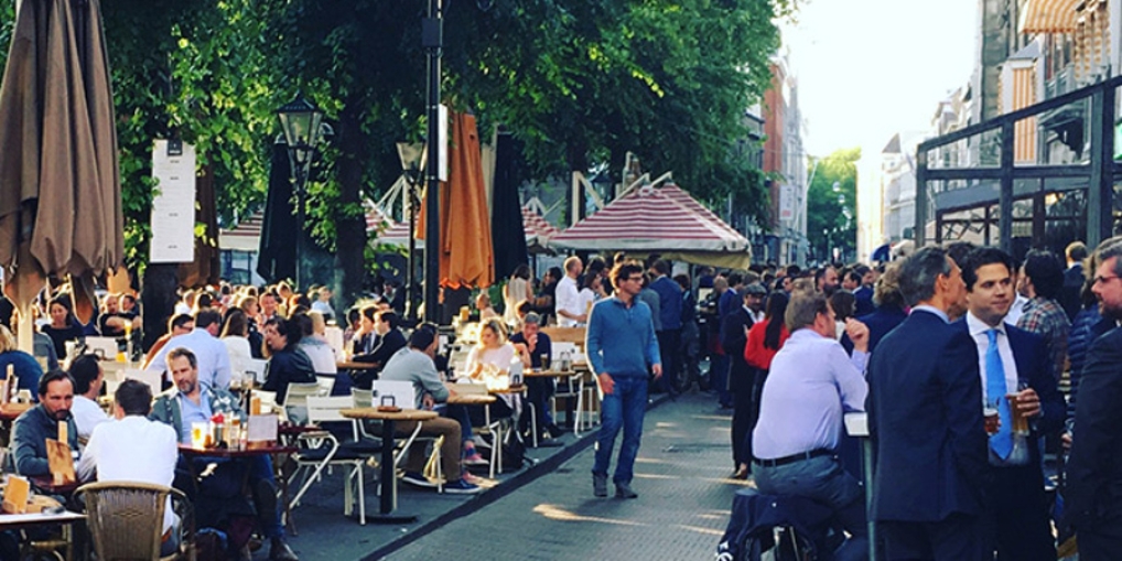 Sfeer op het Plein in Den Haag. Mensen genieten buiten op een terrasje.