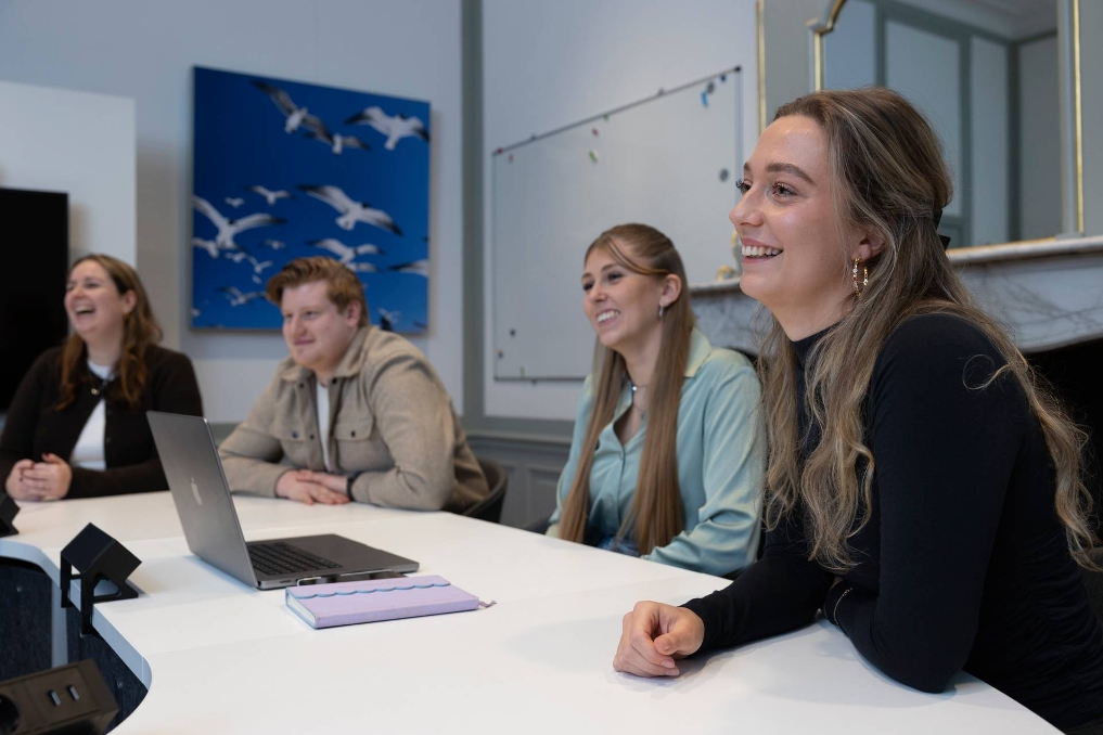 Trainees van de Starterspool Communicatie lachend met elkaar om de tafel