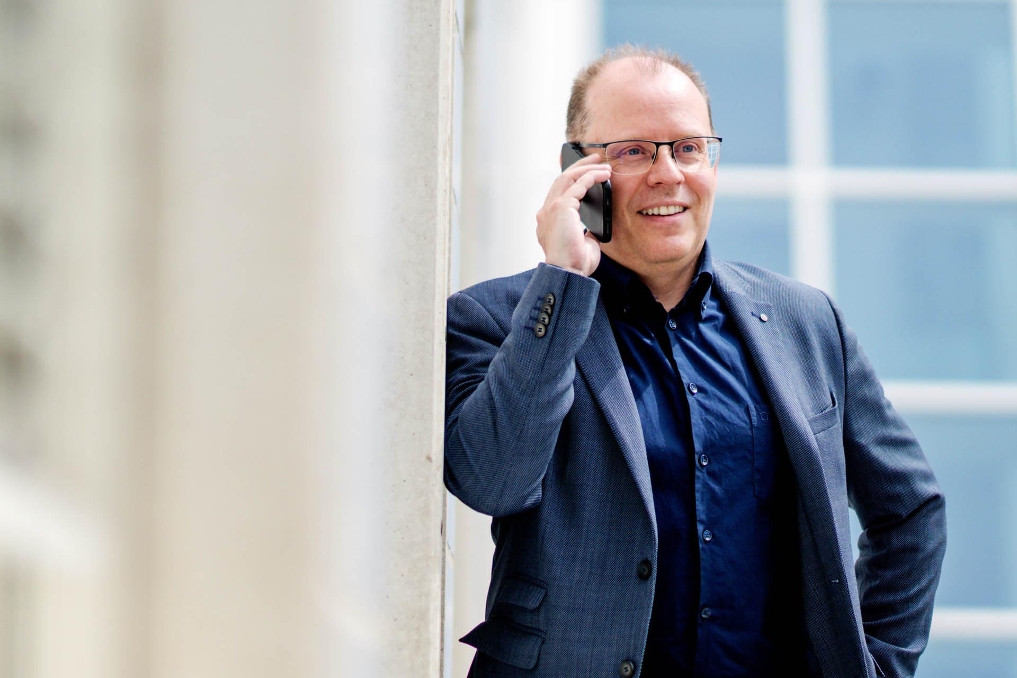 Man voert een telefoongesprek in een kantooromgeving.