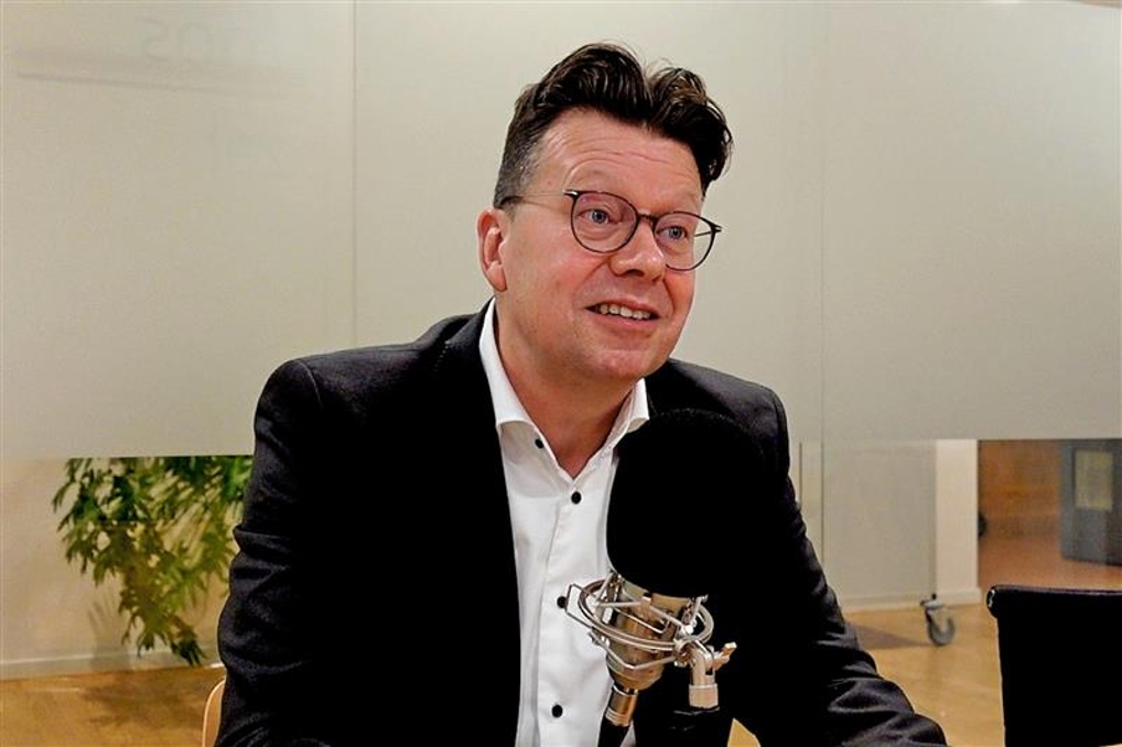 man met bril spreekt in microfoon