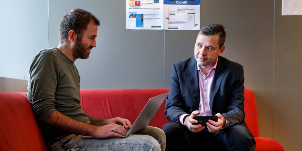 André en collega in gesprek met verschillende mobiele devices bij de hand