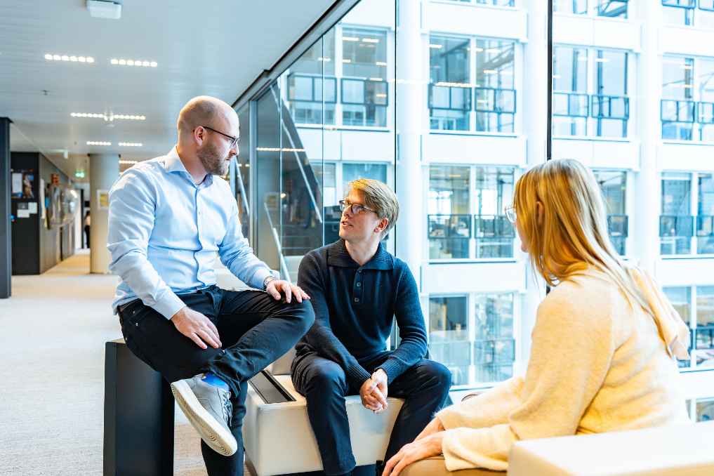 Collega-juristen bij de Rijksoverheid. 3 collega's op een bank in gesprek bij het ministerie van IenW